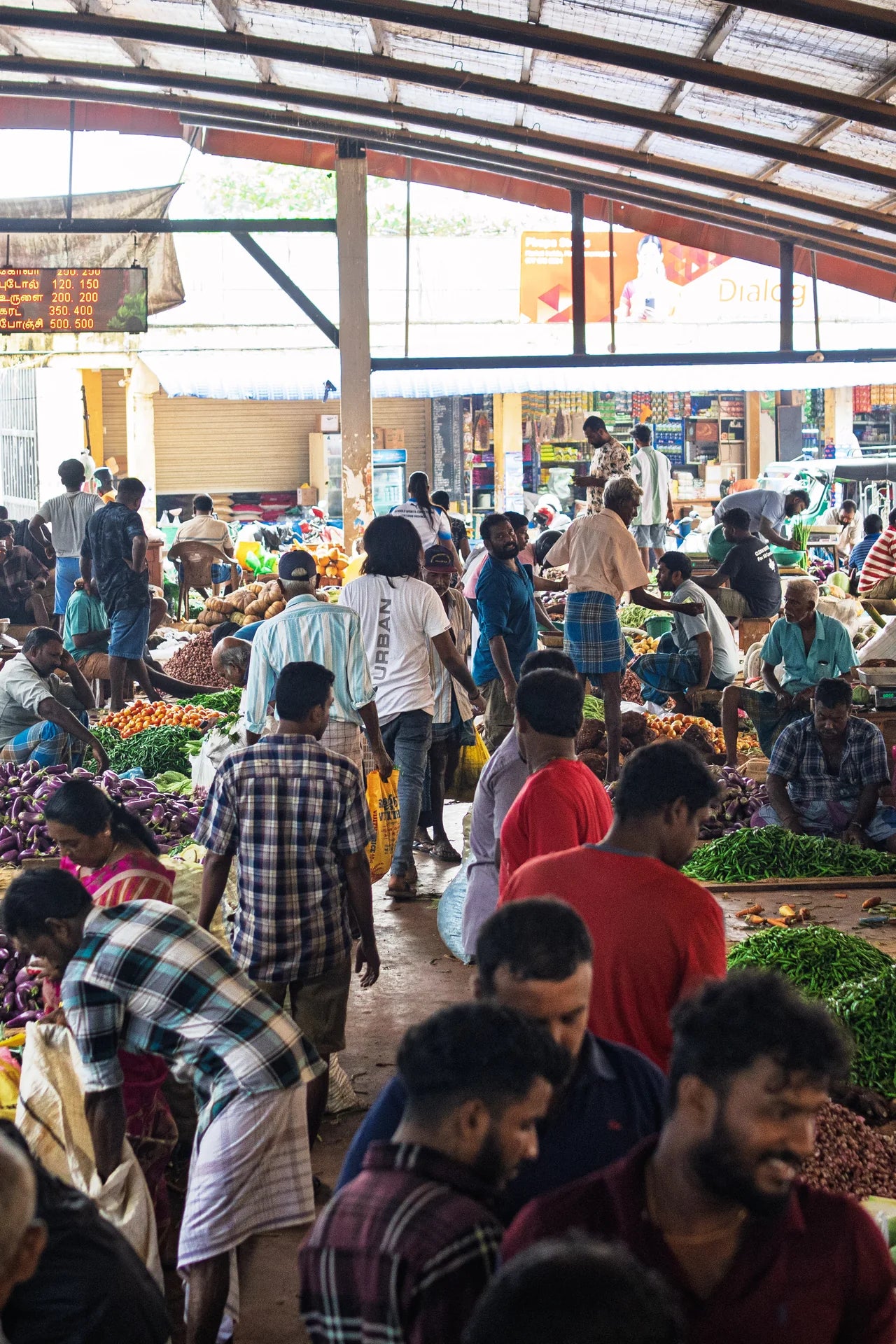 Markthändler an einem überdachten Marktstand in Jaffna Sri Lanka, hält ein Bündel frisches Gemüse in der Tüte - tamilischer Wochenmarkt